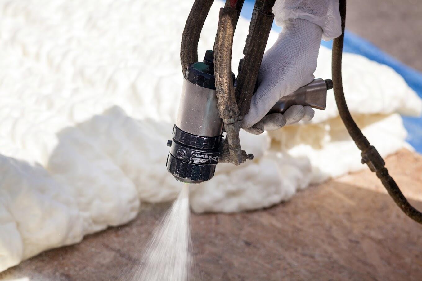 Technician applying spray foam insulation with professional equipment